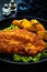 Crispy breaded seared chicken cutlet with baked pumpkin on wooden table