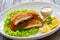 Crispy breaded seared chicken cutlet with lemon slices and fresh vegetables on wooden table