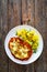 Crispy breaded seared pork chop with fried white mushrooms, cheese and boiled potatoes on wooden table