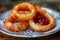 Crispy fried onion rings served on a vintage plate with ketchup for delicious appetizer options, ideal for menus and food blogs