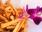 Crispy golden fresh French fries with purple orchid