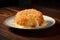 A crispy, golden fried cheese dish with cheese oozing out, served on a white plate on a wooden table