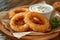 Crispy golden onion rings served with dipping sauce on a wooden plate