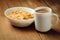 Crispy healthy dry cereal flakes in white plate on wooden background and cup of coffee with milk