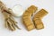 Crispy oatmeal biscuits on the white surface with wheat ears and a glass of milk.