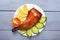 Crispy poultry meat, cooked on a grill with sliced lemon, cucumber and tomatoes on white plate on a wooden table background. Natur