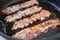 Crispy smokey bacon slice or strip. Unhealthy fat food, fattenig ingredient. Red Thin slice or strip or rashers of bacon is fried