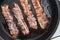 Crispy smokey bacon slice or strip. Unhealthy fat food, fattenig ingredient. Red Thin slice or strip or rashers of bacon is fried