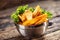 Crispy spiced potato wedges in a metal bowl with salad leaf on dark wood