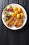 Crispy steaks in sesame breading with new potatoes and fresh salad close-up on a plate. Vertical top view