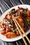 Crispy, tasty chicken pieces stir-fried with a generous amount of dried chillies and Sichuan pepper close-up in a plate. vertical