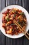 Crispy, tasty chicken pieces stir-fried with a generous amount of dried chillies and Sichuan pepper close-up in a plate. vertical