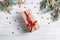 Cristmas present wraped in craft paper with red ribbon on white wooden background with fir tree branches