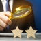 A critic holds a magnifying glass over two stars. Rating, feedback and review of a restaurant or hotel. Quality of service.