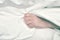 Critically ill patient clasps the bed sheet in the hand