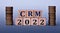 CRM 2022 - acronym on wooden cubes on a light background with coins