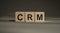 CRM, customer relationship management, loyalty program, repeat purchase frequency concept, on wooden blocks over gray background