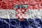 Croatia flag depicted in paint colors on shiny crumpled aluminium foil closeup. Textured banner on rough background