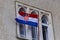 Croatian flag flutters in the wind in front of windows of medieval architecture in Trogir