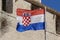 Croatian flag waving in the wind in front of the wall of medieval architecture in Trogir