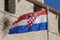 Croatian flag waving in the wind in front of the wall of medieval architecture in Trogir