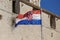 Croatian flag waving in the wind in front of the wall of medieval architecture in Trogir