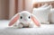 Crochet white bunny on child bed. Cute handmade toy. Japanese amigurumi