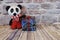 A crocheted panda stands next to a gift box with one paw on it