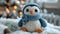 A crocheted penguin wearing a blue hat and scarf, handcrafted knitted miniature toy.