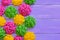 Crocheted roses. Yellow, pink and green crocheted roses. Colourful floral decorations on a wooden background with copy space