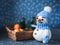 Crocheted white snowman in a blue hat with a branch of a basket with tangerines