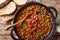 Crock pot beans with ground beef, bacon in a spicy sauce closeup on the table. Horizontal top view