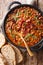 Crock pot beans with ground beef, bacon in a spicy sauce closeup on the table. Vertical top view