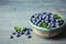 Crockery with juicy fresh blueberries and green leaves
