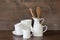 Crockery, porcelain, white utensils and other different stuff on wooden tabletop. Kitchen still life as background for design. Cop