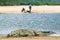 Crocodile in sun near two fishermen in rear-view at Greater St. Lucia Wetland Park World Heritage Site, St. Lucia, South Africa
