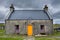 The croft house whitehouse, with orange door and dark red windows, on a stormy, cloudy day