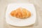 croissan in a white plate on a marble background/croissan in a white square plate on a marble background. Top view