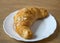 Croissant with almond flakes on a white plate. Homemade puff pastry.