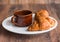 Croissant with chocolate on a white plate, a cup of coffee