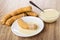 Croissant with condensed milk, heap of croissants, bowl with milk on wooden table