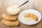 Croissant with condensed milk on saucer, croissants, spoon in bowl with milk on table