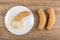 Croissant with condensed milk on saucer, croissants on table. Top view