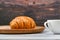 Croissant and a cup of coffee on the table. Fresh french croissant. on a wooden background. View from above. Morning breakfast