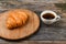 Croissant and a cup of coffee on the table. Fresh french croissant. on a wooden background. View from above. Morning breakfast