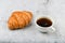 Croissant and cup. on a specific background. Fresh french croissant. on a wooden background. View from above. Morning breakfast