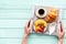 Croissant, fruit and coffee with cream for breakfast on the tray on mint green wooden background top view mockup