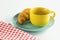 Croissant on green dish with yellow cup coffee and fabric red alternating white.