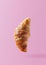 Croissant levitating or flying on pink background. Levitation, fly scene