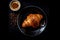 Croissant lying on a black plate, a mug with coffee, top view, dark style photography shot, ad background.